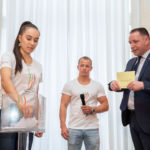 Under the leadership of Christian Schmit (presenter, right), Tabea Alt (internationally decorated artistic gymnast) and Fabian Hambüchen (former artistic gymnast and Olympic champion 2016 at the horizontal bar) draw the competition days. Credit: Messe Stuttgart